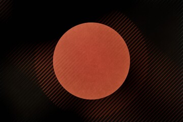 burnt-orange circle dominates a dark background overlaid with diagonal, subtly glowing lines creating a sense of depth and movement.  The circle has a slightly rough, almost fabric-like appearance