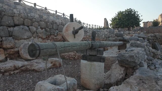 Camera approaches an ancient millstone or olive press at the Kanlıdivane (Kanytelleis) ancient city ruins in Mersin, Turkey. Historical site of traditional grain or olive oil production.