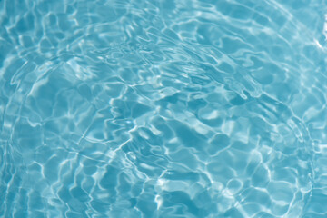 Blue water with ripples on the surface. Defocus blurred transparent blue colored clear calm water surface texture with splashes and bubbles. Water waves with shining pattern texture background.