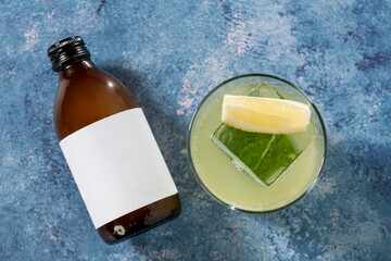Top view of brown bottle and refreshing cocktail on blue surface
