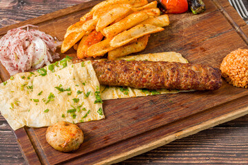 Traditional Adana kebab with fries, lavash, bulgur and onion salad