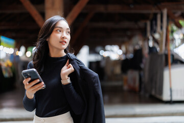 Obraz premium Businesswoman using smartphone walking in a market hall