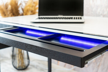 Top view of open wooden drawer white office table with blue lightning. Modern office table with...