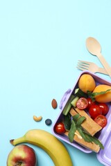 Vertical photo of lunchbox with healthy snacks and fruits on a blue background