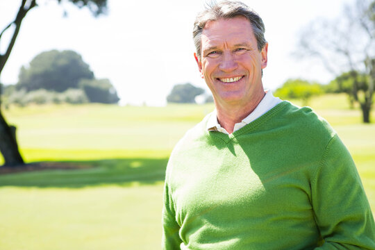 Senior African American man standing on golf course wearing green sweater, white shirt, copy space - Powered by Adobe