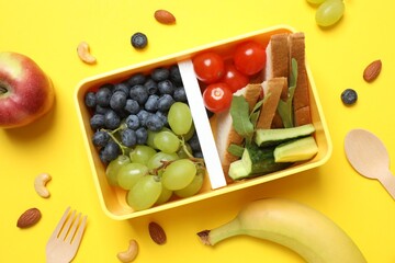 Healthy food concept with lunch box with fresh fruits, nuts, sandwich and vegetables