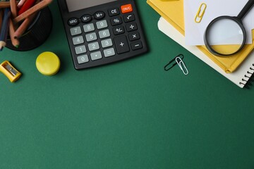 School stationery on a colorful green surface, including notepads, pencils, calculator