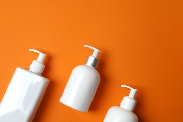 Sunscreen bottles on orange surface, space for text