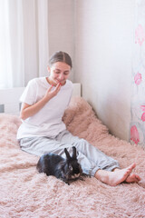 Obraz premium Girl relaxing on bed with pet rabbit.
