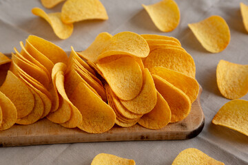 Bacon flavoured potato chips on a wooden board, side view.
