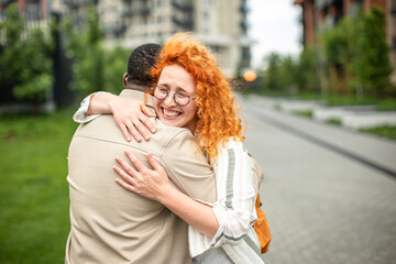 Cheerful moment shared between a black man and a ginger woman in a lush green urban setting
