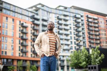 Black man standing confidently in front of a modern urban apartment building