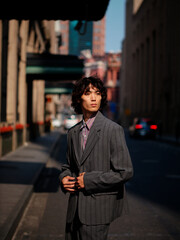 Portrait of handsome Chinese young man wearing gray suit posing in the street, young guy with black...
