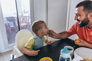 Mother teaching her son to cut vegetables in the kitchen. Scene shows family routine, parenting...