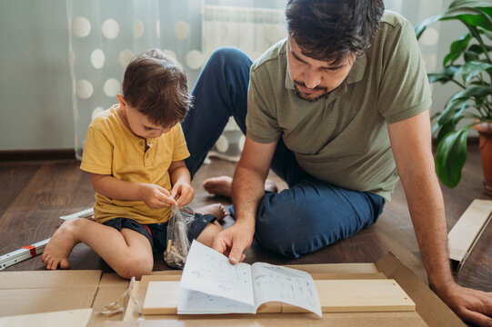 Father reading instruction manual with son at home