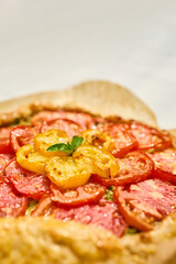 A delicious tomato galette is displayed on parchment paper, showcasing layers of vibrant red and yellow tomatoes atop a flaky crust in a warm kitchen atmosphere.
