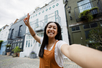 Happy tourist taking selfie in front of colorful urban houses outdoors