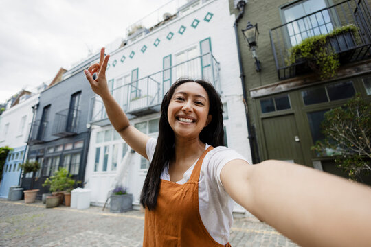 Happy tourist taking selfie in front of colorful urban houses outdoors