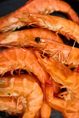Freshly grilled shrimp rest on a black grill plate, with vibrant green grass providing a lively backdrop in a sunny outdoor environment, suggesting a barbecue gathering.