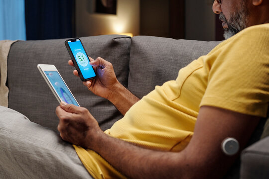 Person using digital app to check glucose level at home on sofa