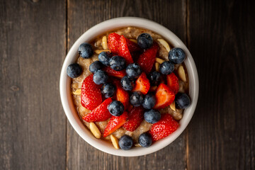Oatmeal with ripe strawberries, blueberries and honey in the bowl. Selective focus.