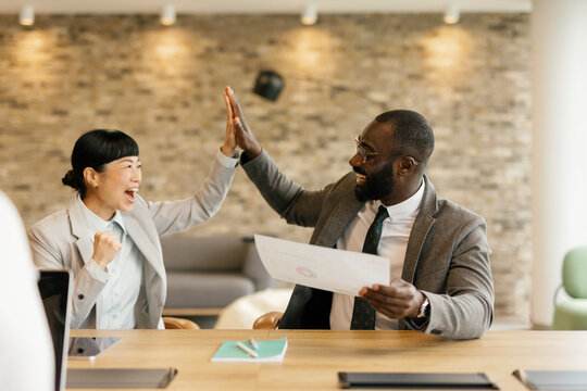 Two business colleagues celebrate success with high five in office