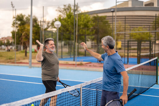 Two people celebrating after tennis match outdoors on blue court