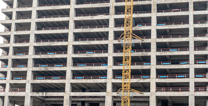 Unfinished floors of a multi-storey building without external walls. Fragment of the facade of a monolithic residential building under construction with crane