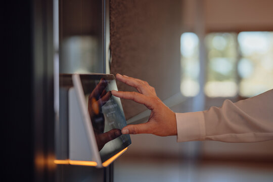 Hand operating a modern touch screen control panel in office setting