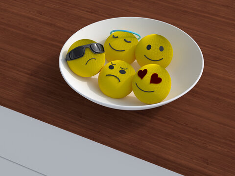 Knitted emoji faces with various emotions in a bowl on wooden table