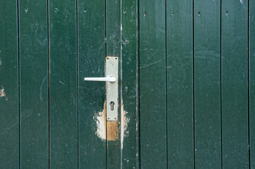 Old green wooden door with metal handle and lock, vintage entrance detail, rustic architecture background
