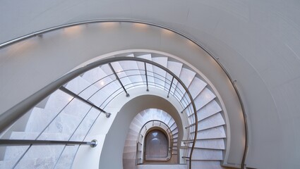 Obraz premium Spiral staircase leads down into a bright, minimalist space with modern railings and smooth walls