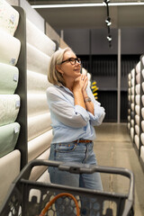 Woman shopping for home improvement supplies in a retail store with various sections for kitchen,...