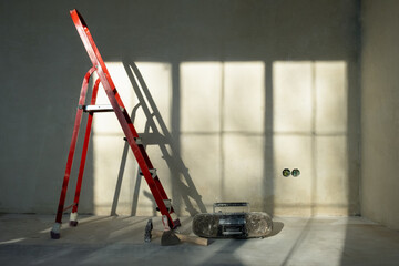 Red ladder stepladder in empty room, without renovation. grey background. Repair concept.
