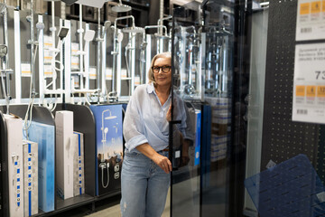 Middle-aged woman enjoys shopping experience in home improvement store exploring various departments