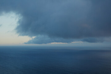 Vast Dark Blue Ocean Under an Overcast and Moody Sky with a Glimmering Horizon at Dusk, Evoking a Sense of Serenity and Immensity