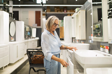 Woman selecting bathroom furniture in a home goods store while enjoying the shopping experience and examining various options