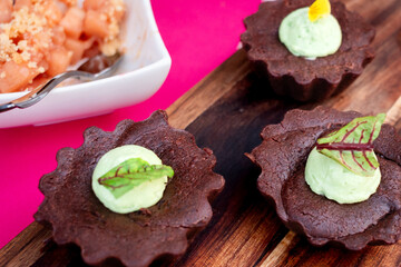Gourmet Chocolate Tartlets with Green Cream on Wooden Board