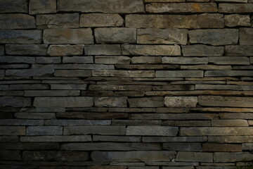 Fototapeta premium texture of a natural stacked stone wall. The image shows uneven, layered stones with rough surfaces and earthy brown tones. Perfect for backgrounds, architectural themes, construction materials, rusti