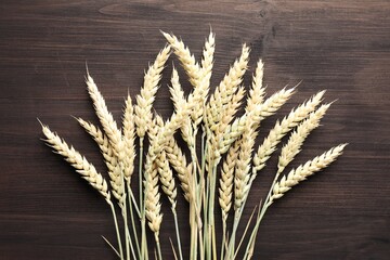 Many wheat spikes on wooden table, flat lay