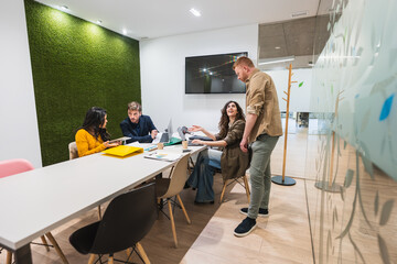 Creative team working together, sharing ideas and using technology in a bright and modern coworking office