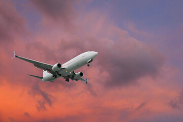 Airplane flying in beautiful sky with clouds at sunset