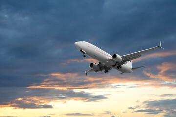Airplane flying in beautiful sky with clouds at sunset