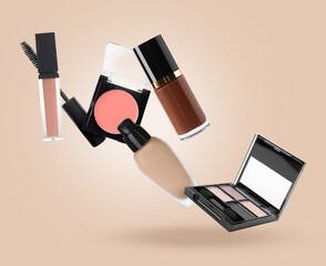 Eyeshadow palette and other makeup products in air against dark beige background