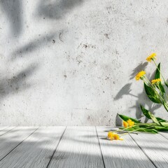 Sun-dappled grey wall backdrop with a bouquet of yellow wildflowers and their shadows cast on a light wood surface