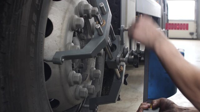 Mechanic aligning truck wheel in professional repair workshop service.