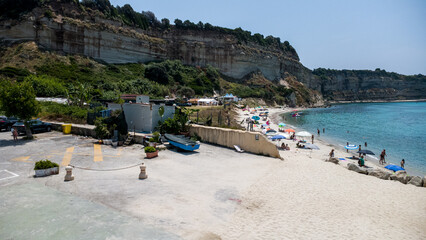 Cliffside Beach Scene – Aerial View of Turquoise Waters, Sandy Shoreline, and Parking Area in Calabria, Italy
