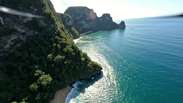 Aerial view of a tropical coastline with steep cliffs lush vegetation a sandy beach and bright turquoise water
