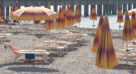 Ombrelloni da spiaggia arancioni e gialli con lettini vuoti sulla costa del Mediterraneo con...