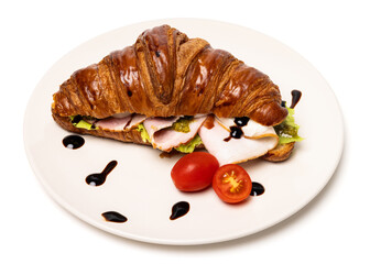 Freshly baked classic delicious fresh organic croissant with ham, cheese, pesto and tomatoes on white ceramic plate isolated on white background